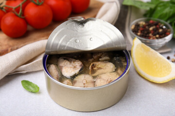 Open tin can with mackerel chunks on grey table