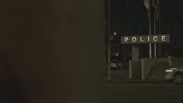 Outside of police station as traffic drives past.