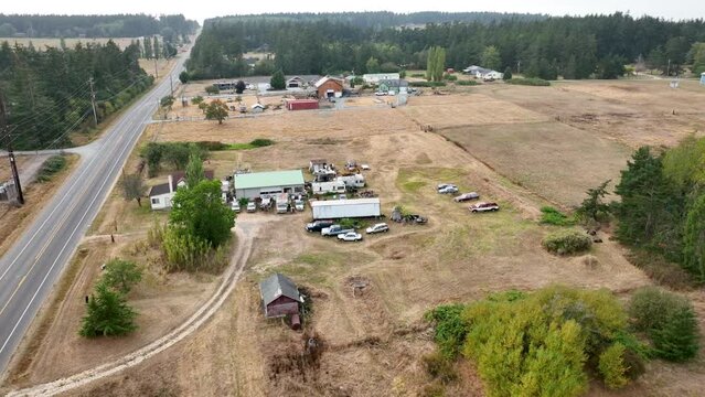 Aerial view of a rural residence with numerous cars parked on the property.