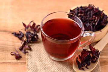 Roselle tea in cup glass with dry roselle on wooden background, Herbal drink for reduction in blood pressure