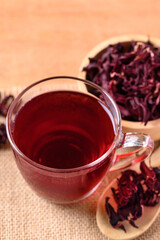 Roselle tea in cup glass with dry roselle on wooden background, Herbal drink for reduction in blood pressure