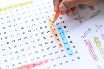 Kid hand doing word search activity in classroom of learning idea in school