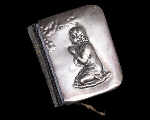 Antique prayer book with silver cover showing kneeling praying child in relief