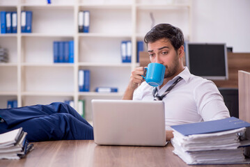 Fototapeta premium Young male employee unhappy with excessive work at workplace