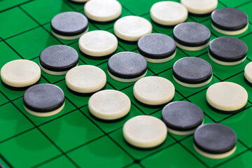 緑色の盤の上に並ぶオセロの白黒の石