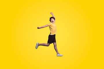 Fototapeta na wymiar Joyful and happy boy expresses his emotions in a jump isolated on a yellow background. Teenager student, isolated background. Excited cheerful. Happy lifestyle