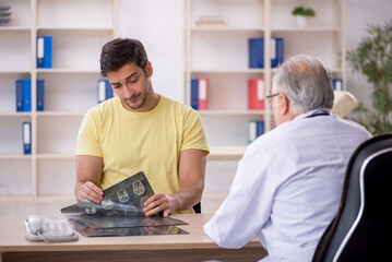 Fototapeta premium Young male patient visiting old male doctor