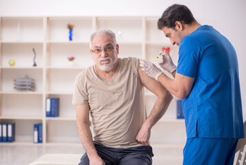 Obraz premium Old male patient visiting young male doctor in vaccination conce