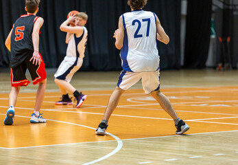 Boys teenagers playing basketball. Group of players in action with a ball. Sports activity, lifestyle.
