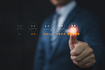 Concept of customer service and satisfaction: businessman touch the virtual screen on the smiley face icon to express satisfaction in service. 5 stars, very impressed.