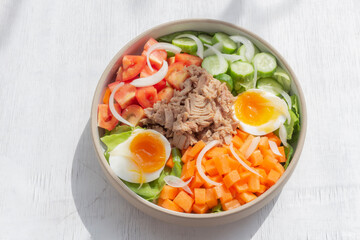 Healthy food tuna salad add egg in white bowl on wood background.