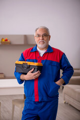 Old male carpenter working indoors