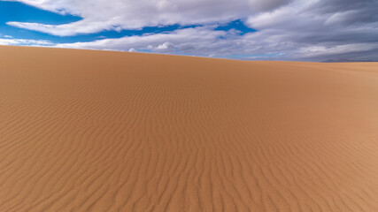 Fototapeta na wymiar Wide sandy desert patterned plateau during bright sunny day in Canary Islands, Corralejo, Spain