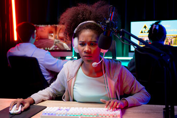Young African American woman wearing headset play video game and live streaming online with microphone at home, gaming and esport for competition or casting game, broadcast and entertainment concept. © NT_studio