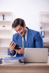 Young male employee drinking alcohol at workplace