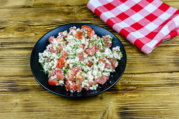 Salad with tomatoes, cottage cheese, dill and olive oil on a wooden table