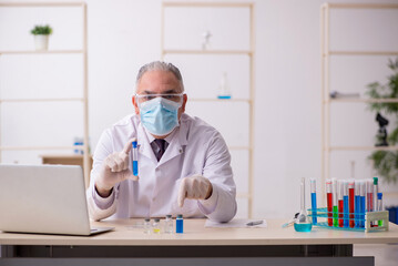 Fototapeta na wymiar Old male chemist working in the lab during pandemic
