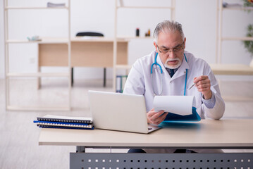 Old male doctor working in the clinic