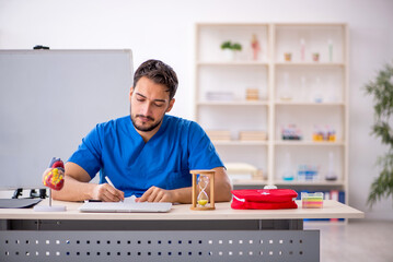 Young male doctor cardiologist in time management concept