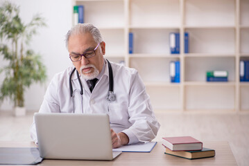 Old male doctor in telemedicine concept