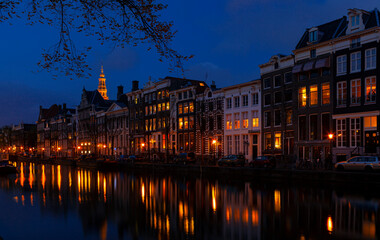 Romantic nocturnal view of Amsterdam: canal in the Red District. Buildings, cars and boats are...