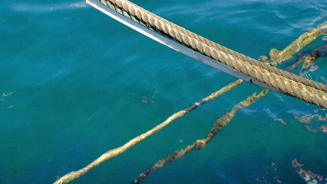 Ropes securing boats with the clear waters of the Aegean Sea in a harbor at Paros Island in Greece