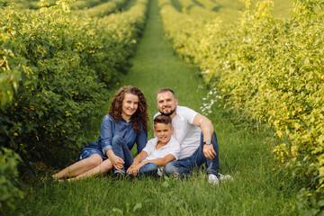 Fototapeta premium Young family looking at the camera while walking in the garden