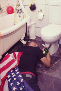 Party, Hangover And Drunk Man In Bathroom Sleeping After Celebration, Festival And House Party In Usa. After Party, Alcohol And Male On Floor By Toilet Of Social Event, New Years Eve And House Party