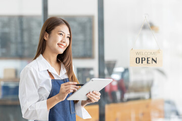 Fototapeta premium Startup successful small business owner sme beauty girl stand with tablet smartphone in coffee shop restaurant. Portrait of asian tan woman barista cafe owner. SME entrepreneur seller business concept