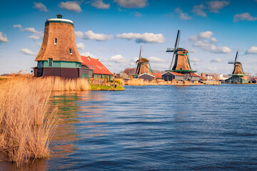 Authentic Zaandam lighthouse and windmills on water channel in Zaanstad willage. Astonishing spring scene of Zaanse Schans, Netherlands, Europe. Traveling concept background..