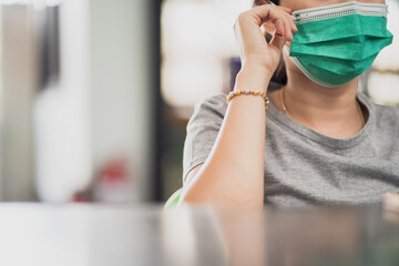 Close-up of young Asian woman wearing a green face mask to prevent respiratory infections....