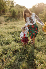 Beautiful family with kid in traditional ethnic dress in a countryside, park