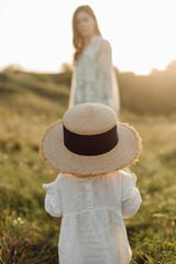 Beautiful caucasian family of father, mother and little daughter posing on camera on background of green field