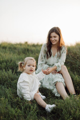 Fototapeta premium Beautiful caucasian family of father, mother and little daughter posing on camera on background of green field