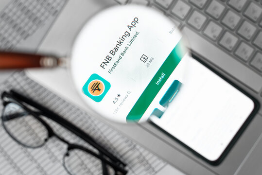 FNB Corporation banking company financial mobile application in online store on smartphone screen at workplace, looking through magnifying glass. Astana, Kazakhstan 04.12.2022
