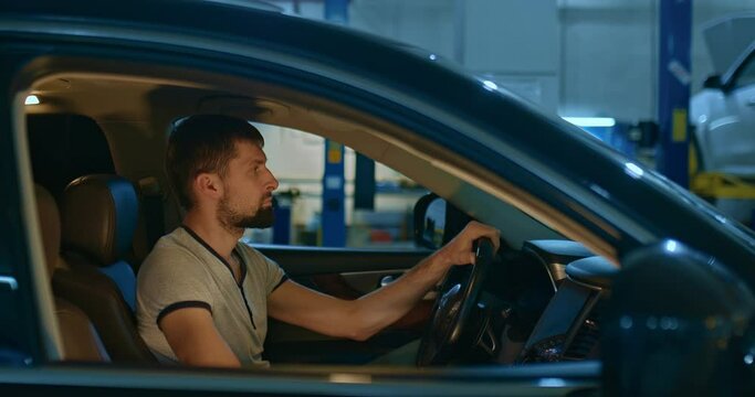 Car pulls into a car service or garage. Driver is driving through a service station or garage. Portrait of the driver in the passenger compartment on the side.