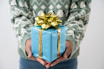 Closeup of hands holding blue gift box.