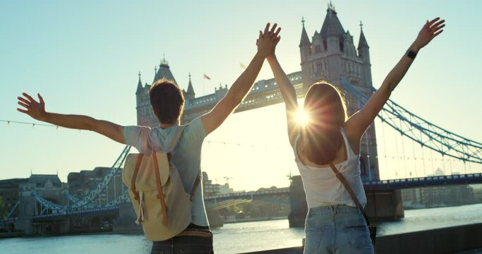 Couple, walking and holding hands to celebrate freedom on bridge in London for love, support and holiday adventure together. City, man and woman happy, travel celebration and hands together in town