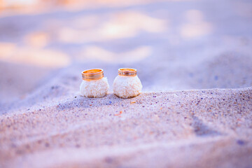 Composition of wedding rings with candies on a sand. Jewelry concept 