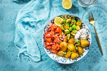 Buddha bowl, healthy and balanced food with baked potatoes, Brussel sprouts and tomato salad