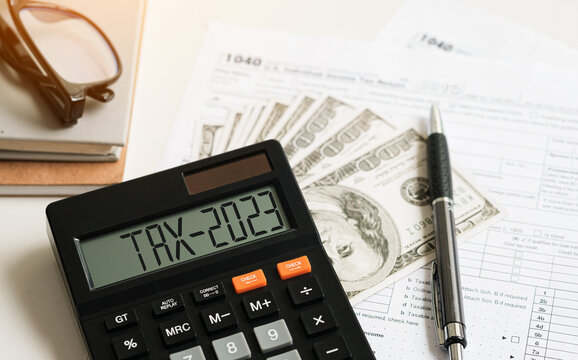 Tax 2023. Word Tax 2023 on calculator. Business and tax concept .Calculator, currency, dollar bills close up. Income Statement. paying the tax rate. Taxation, taxes burden. Business concept..