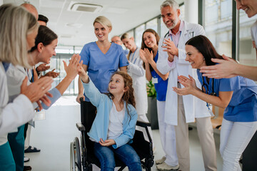 Medical staff clapping to little girl patient who recovered from serious illness.
