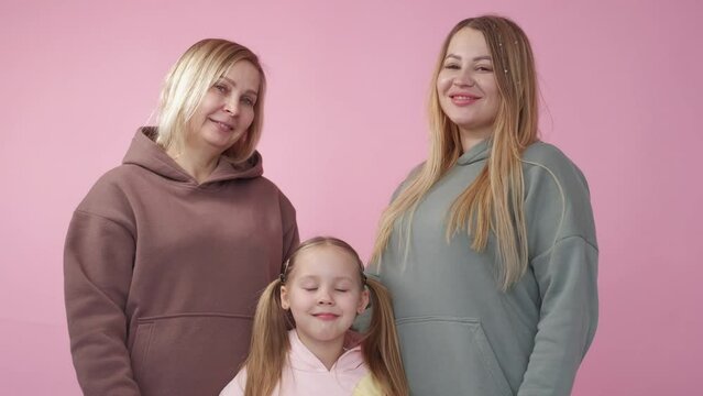 Family photo. Happy moments. Female generation. Pretty smiling girl posing together with mother and grandmother on pink background.