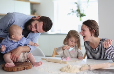 Young parents playing with children in the kitchen