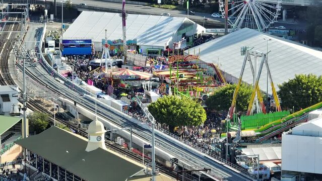Aerial shot of Brisbane Showgrounds during the Ekka carnival celebration, with track station in centre view, with very busy crowd attending the rides and attractions, Brisbane QLD