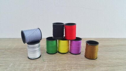 Colorful sewing thread spools on wooden table with white background
