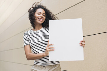 Happy young woman holding blank white banner sign, Beautiful african american girl showing white...