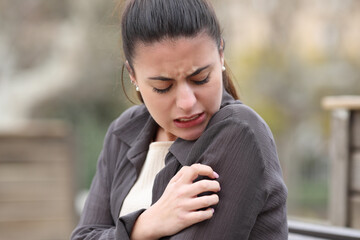 Woman scratching itchy arm in a park