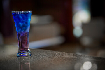 Splash chilled refreshing summer blue cocktail with ice cubes on blur background
