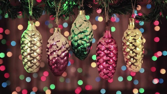 Glass vintage toys Christmas cones on a background of glowing lights. New Year's multi-colored garlands in defocus. Holiday card with bokeh. Abstract background for captions and text. UHD 4K.